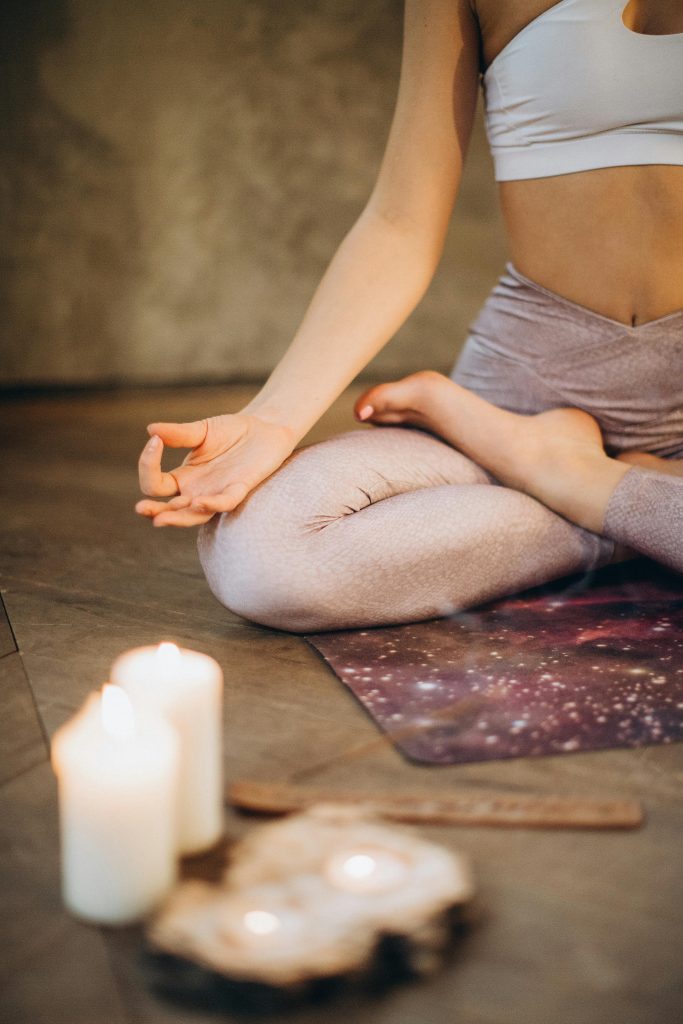 pexels-photo-3822621-3822621 A woman practicing yoga indoors in lotus pose with candles creating a calming atmosphere.